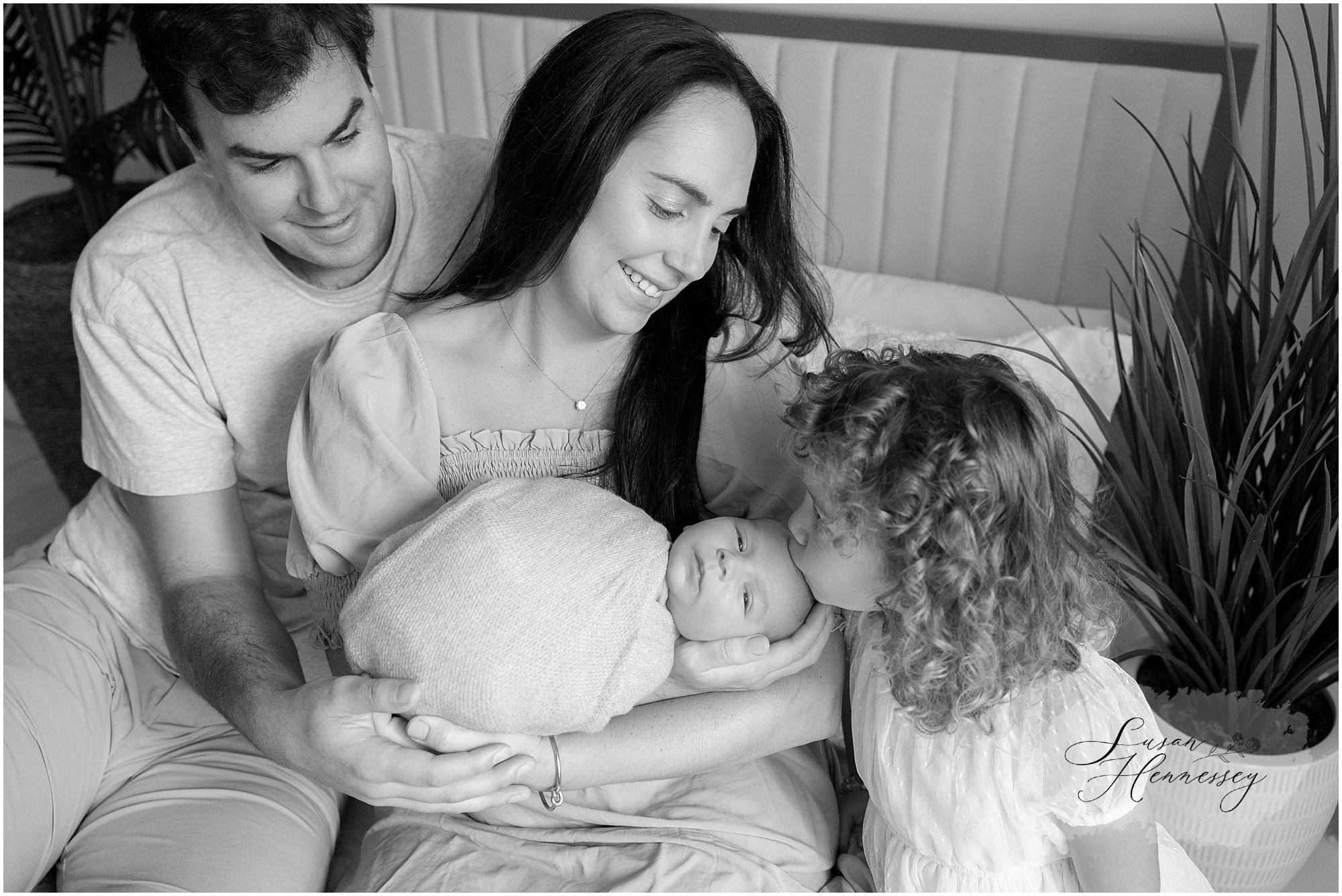 Newborn family portrait featuring parents, baby Carson, and proud big sister
