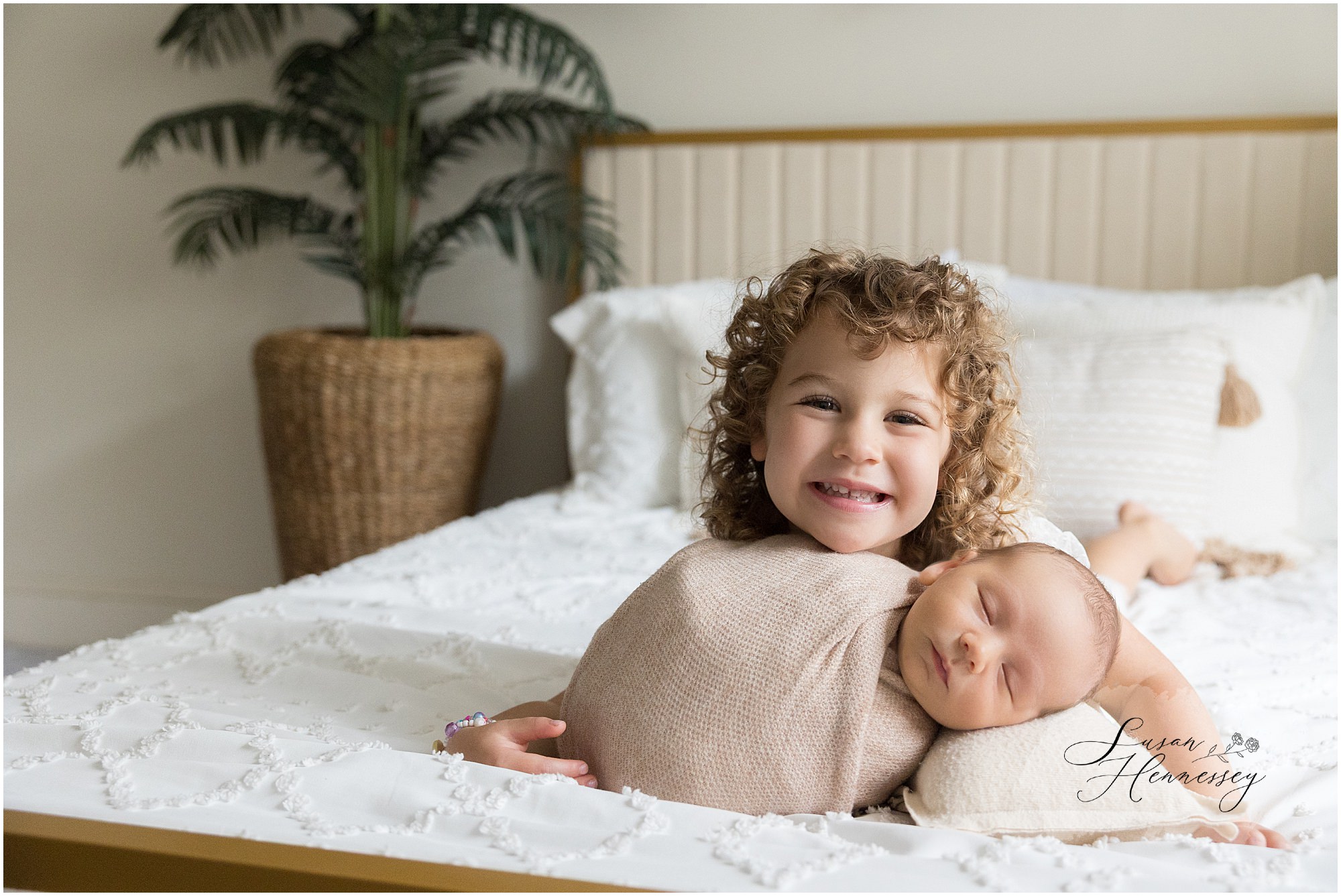 Proud big sister cuddling newborn baby Carson during sibling portraits