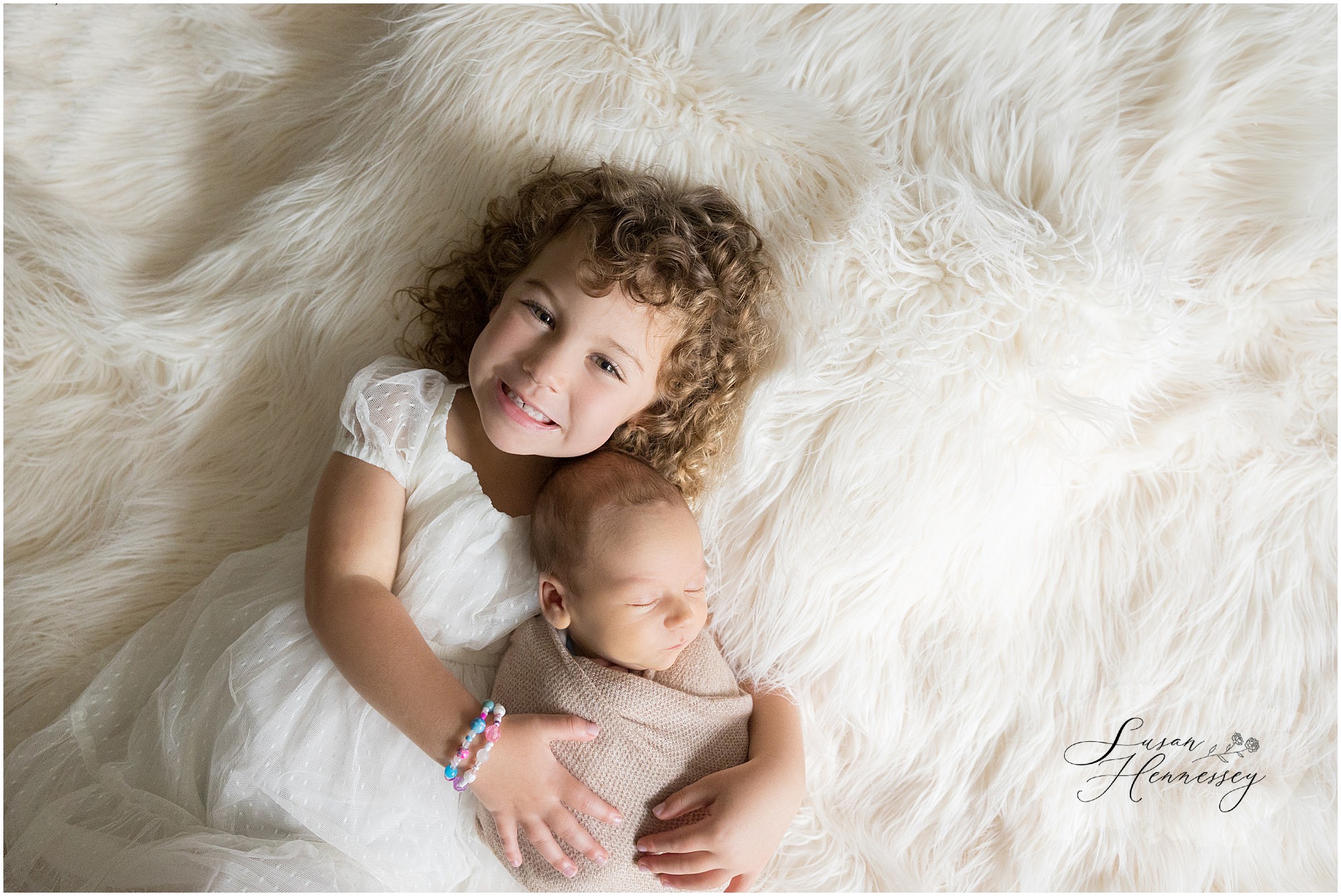 Big sister smiling while snuggling baby Carson