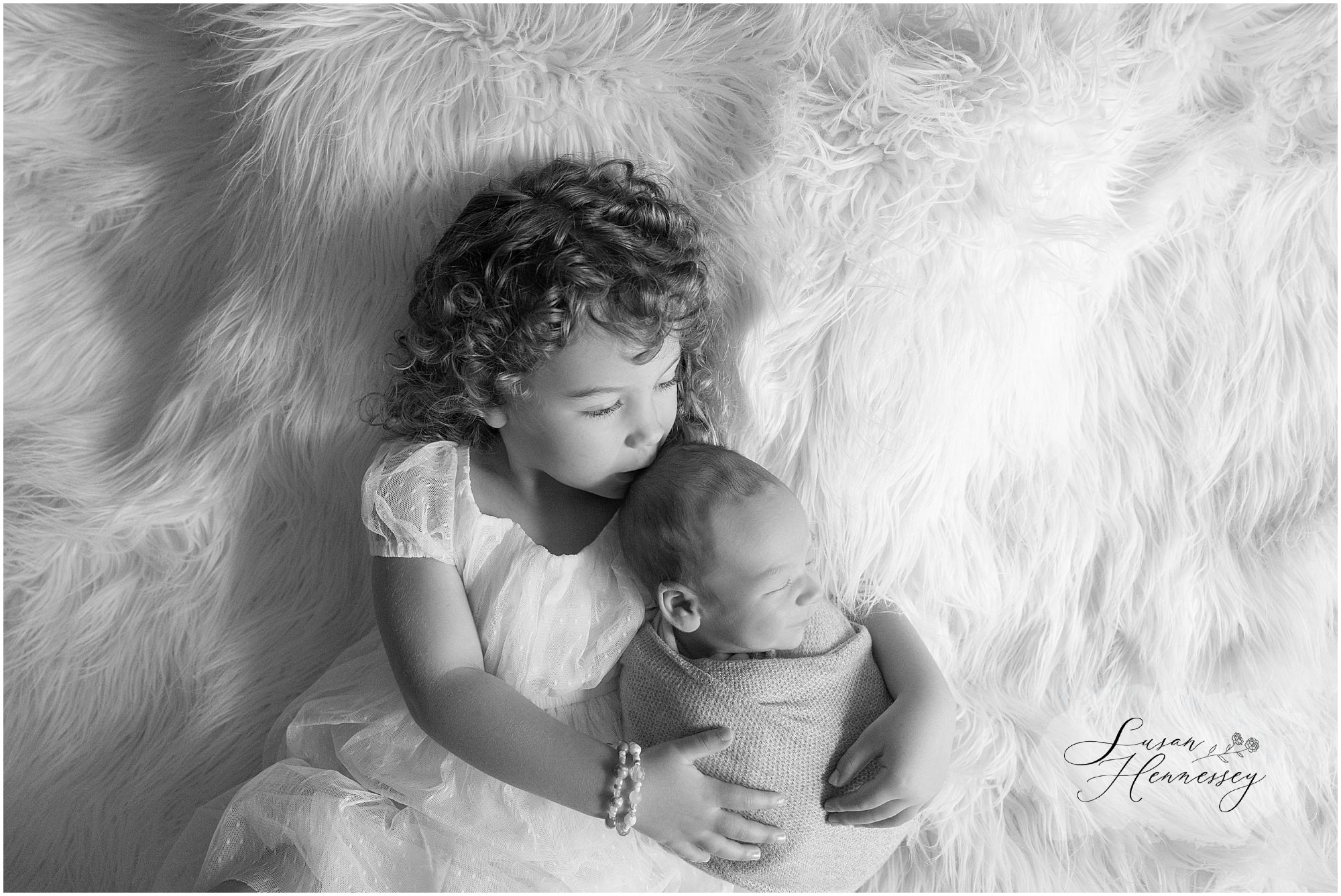 Big sister kissing newborn baby Carson on the forehead