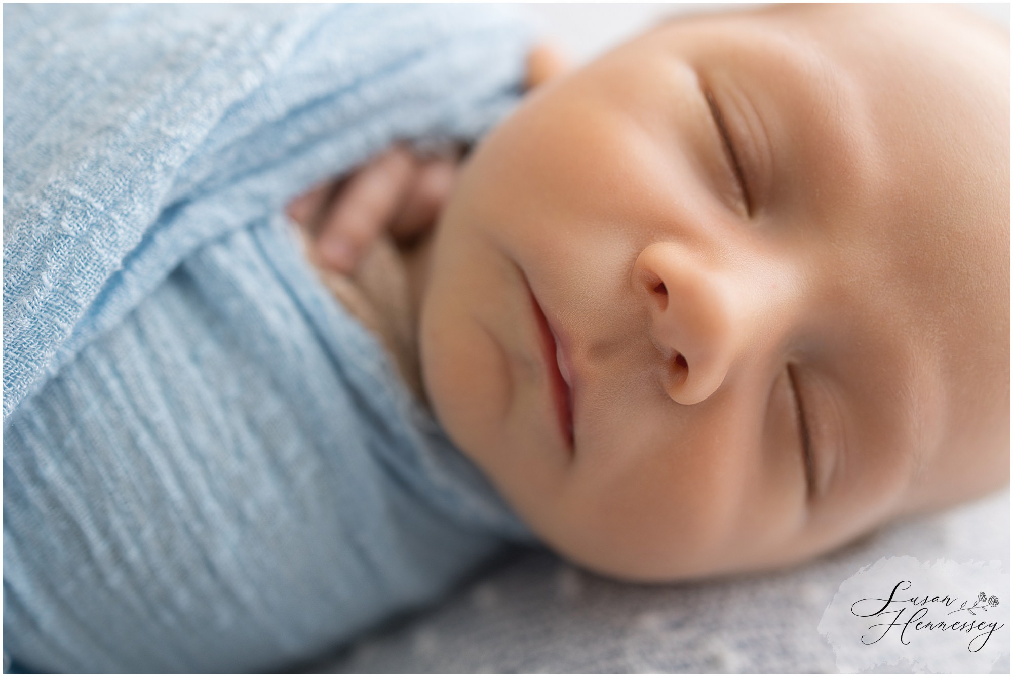 Newborn baby Carson posed in soft blue wraps during studio session