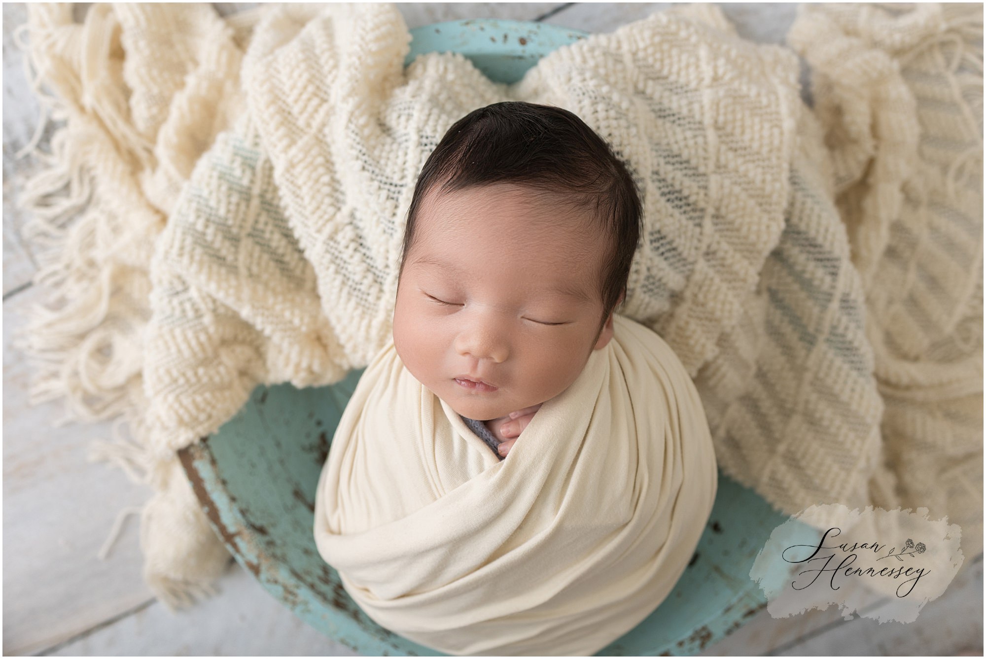Baby Leo sleeping peacefully in blue newborn photography prop