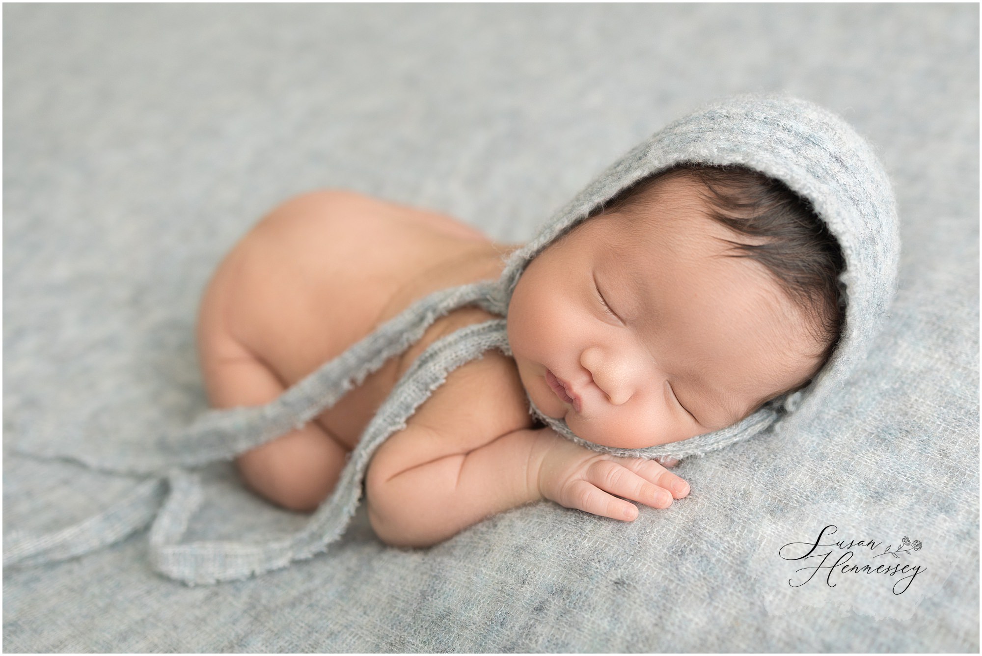 Minimalist newborn portrait of baby Leo wearing a blue bonnet hat
