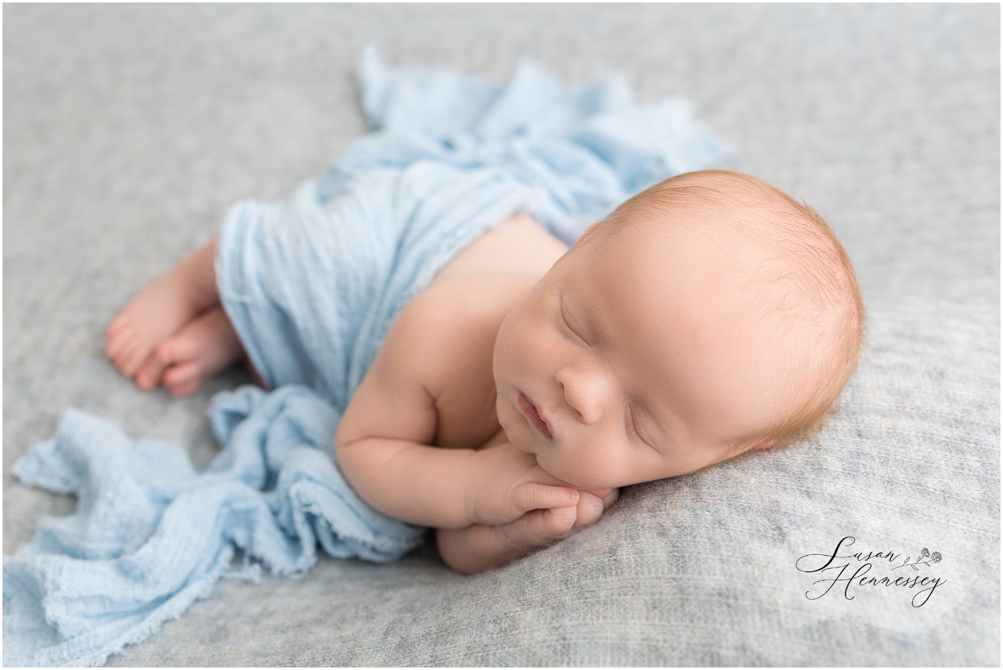 Newborn baby Jack sleeping peacefully in a classic blue wrap.